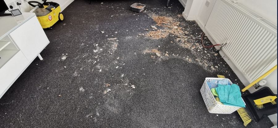 HMO living room carpet covered in ceiling debris after a leak, before cleaning