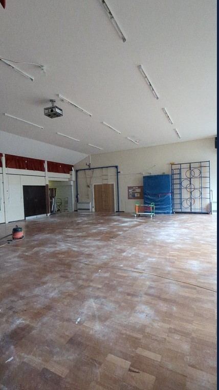 Primary school main hall floor before the post-refurbishment clean, covered in dust and debris